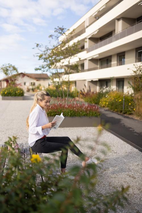 Jeune femme qui lit un livre sur un banc
